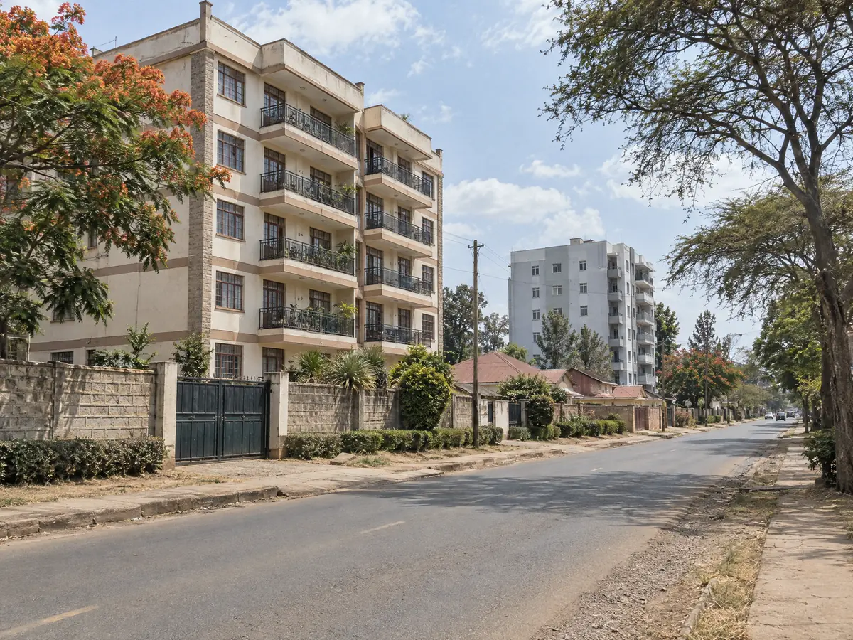 A residential street with apartment blocks and a flame tree in Thika